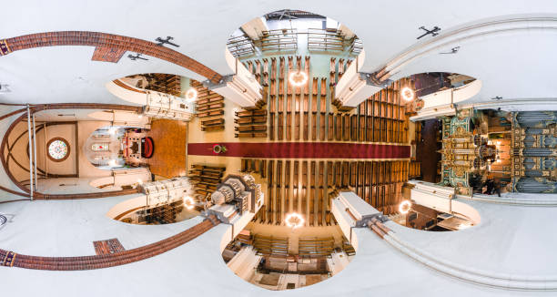 Aerial view of a cathedral interior featuring a central aisle with wooden pews, an ornate altar, a grand organ, and intricate ceiling designs with chandeliers.