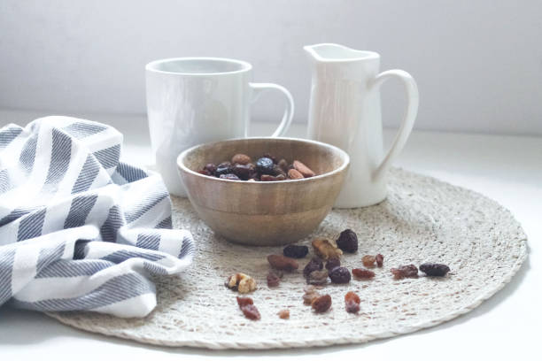 A cup of coffee , milk and plate with nuts on a white background