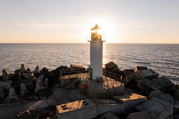 Lighthouse Silhouette on Breakwater at Sunset with Ocean Horizon
