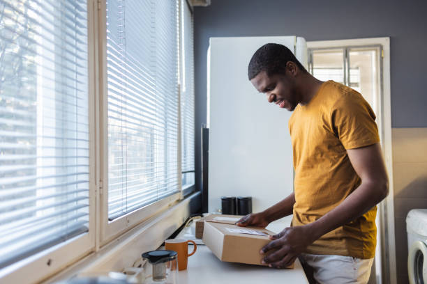 istock Man inspecting a package delivery in a home kitchen 2189654823