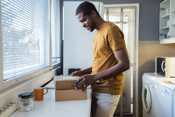 istock Man inspecting a package delivery in a home kitchen 2189655080