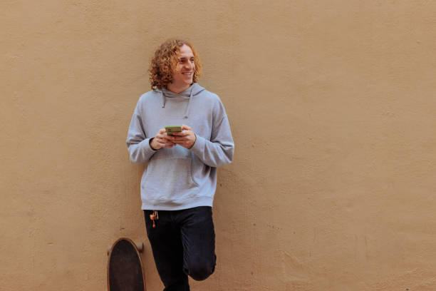 istock Young man with skateboard using a smartphone and smiling 2189655441