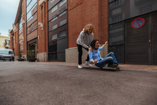 istock Young man pushing woman on skateboard in urban setting 2189655477