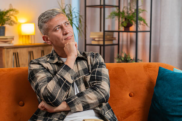 istock Thoughtful man rubbing chin looking aside with pensive expression pondering a solution at home room 2189663496