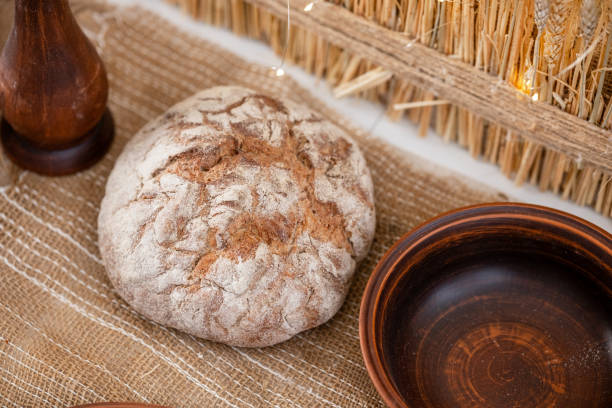 Warmly baked bread rests on a textured tablecloth, surrounded by wooden bowls, embodying the spirit of holiday gatherings and seasonal joy during Christmas and New Year celebrations.