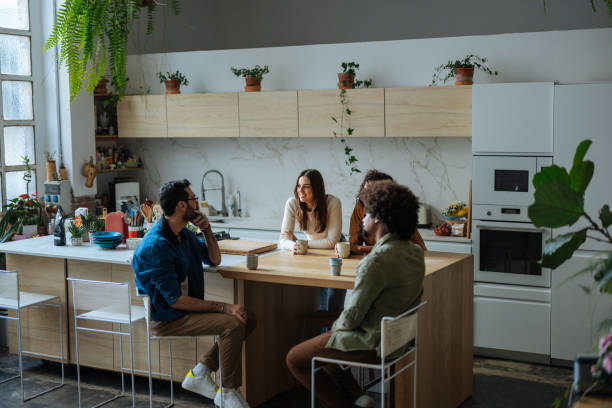 istock Cheerful young adults chatting and drinking coffee in modern kitchen 2189664188