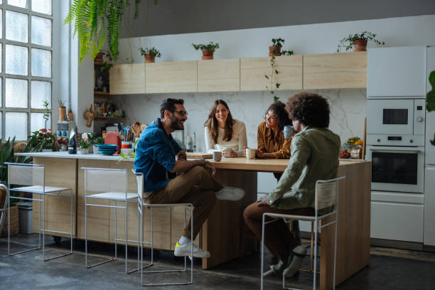 istock Four young adults enjoying coffee and conversation in modern kitchen 2189664191