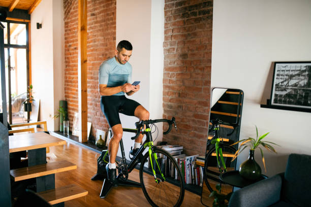 istock Athlete using smart phone during workout on cycling turbo trainer at home. 2189664284