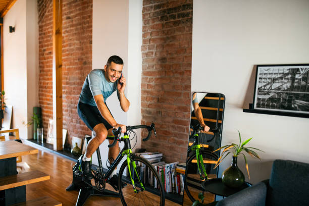 istock Talking on smart phone during cycling at home on turbo trainer. 2189664286