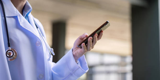 istock Asian doctor using smartphone in hospital corridor 2189680456