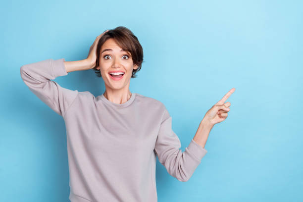 istock Portrait of positive speechless girl bob hairdo dressed gray pullover directing empty space offer poster isolated on blue color background 2189681632