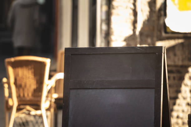 istock A black, empty chalkboard sign (or sandwich sign) stands outside a Dutch bar in warm sunlight. The blank surface invites new messages, reflecting the simple ways local businesses connect with passersby. 2189684578