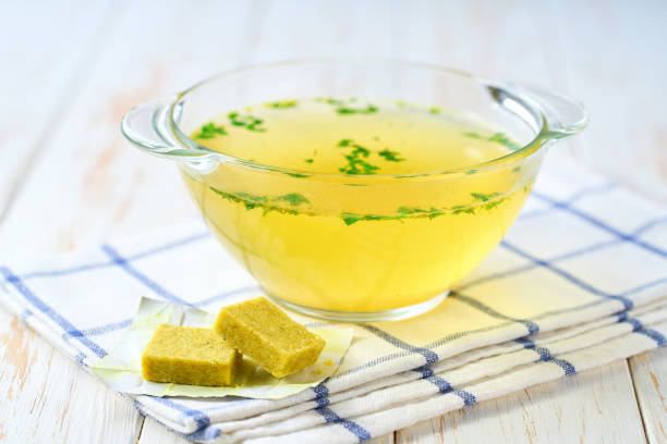 Chicken stock concentrate cube with ready to eat bouillon in a bowl on a kitchen table .