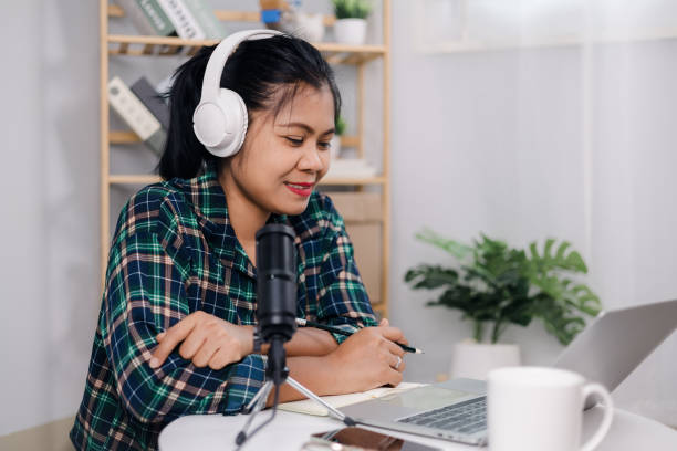 istock Online live streaming at home, Record podcast interview for radio, Content creator concept. Woman wearing headphones sitting at a desk speaking into microphone and recording a podcast. 2189692514