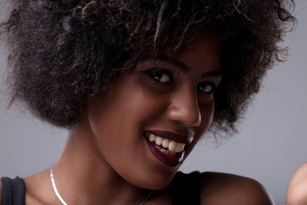 Portrait of a beautiful young african american woman with an afro hairstyle, smiling and looking at the camera with a confident and friendly expression