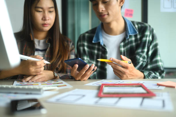 istock Designers discussing user interface ideas while reviewing a smartphone and design sketches on the desk 2189709678