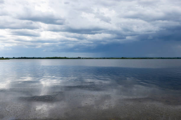 lake and trees on the shore before a storm, lake and sky with clouds in cloudy weather