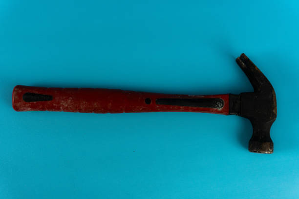 hammer with a red rubber grip rests on a blue background