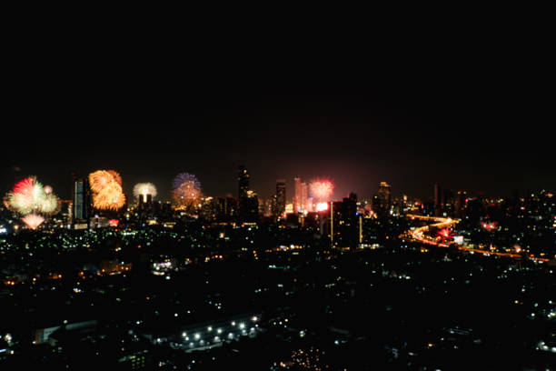 Blur background landscape thailand countdown showing flowers fireworks bright nice viewing over buildings towers city in midnight new year. Shiny light fireworks festival modern city on dark sky night