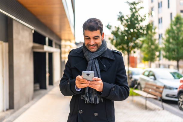 istock Elegant man using phone walking along the city 2189725164