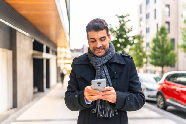 istock Elegant man in winter clothes using phone smiling walking outdoors 2189725182