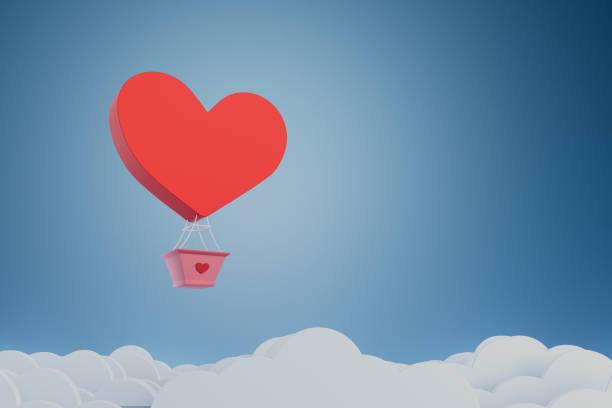 A red heart shaped balloon is floating in the sky. The balloon is carrying a basket with a heart inside. The sky is blue and cloudy. Concept of love and happiness