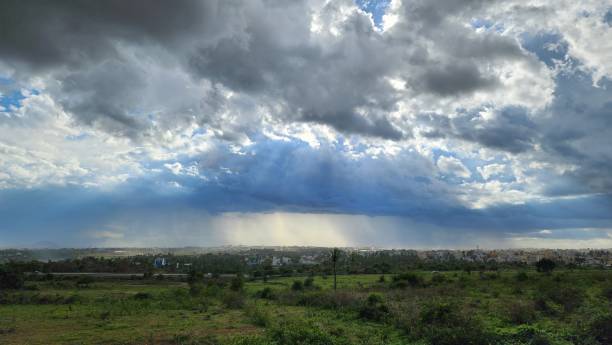 istock Dramatic clouds with sunlight breaking through over a cityscape and green fields. Bengaluru, India 2189735834