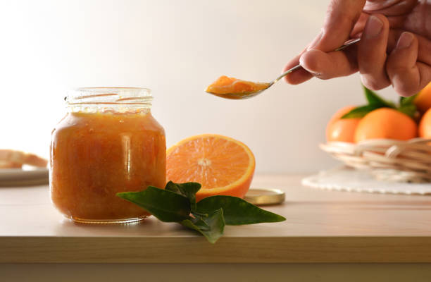 istock Jar of orange jam and hand with a spoon full 2189735916