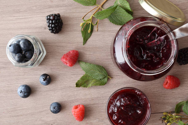 istock Jars with forest fruits jam on a wooden bench 2189735940