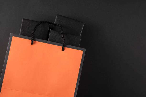 Shopping bag with gift boxes on black colored background with copy space