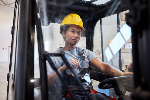 istock Black female worker driving forklift in storage room. 2189738488