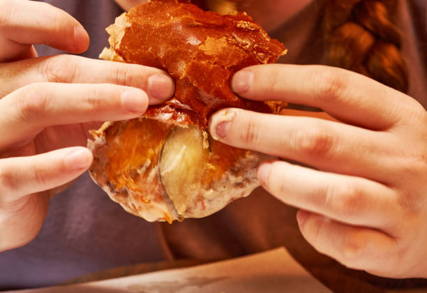 A girl in a cafe eats a hamburger. Close-up.