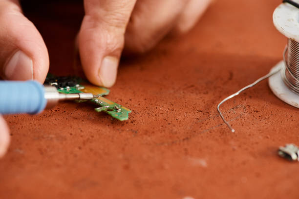 A skilled technician repairs a circuit board with tools on a workbench in the service center.