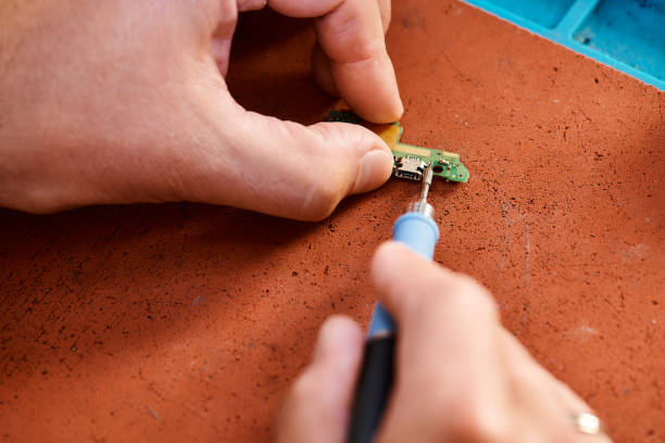 A skilled technician is focused on fixing an electronic component at a service center.