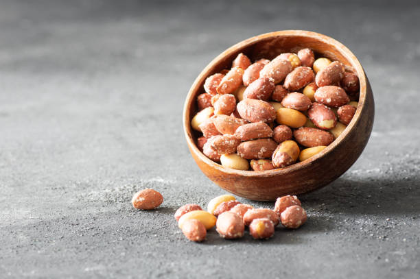 Roasted salty peanut without Shell in bowl or burlap sack on rustic background, concept of nuts