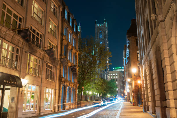 Montreal, Quebec, Canada - August 18 2021 : Night view of Old Montreal. Saint-Sulpice Street (Rue Saint-Sulpice). Notre-Dame Basilica.