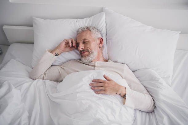 istock Serene morning with elderly man peacefully waking up in white bed, enjoying leisure and comfort at home 2189748354