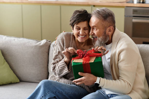 istock Mature couple sharing a joyful moment while opening a gift at home 2189749687