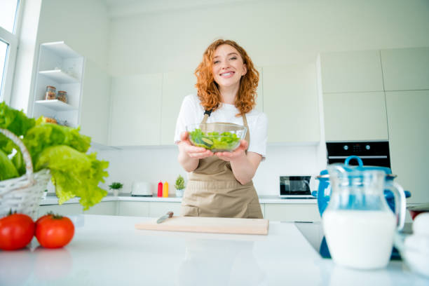 istock Charming young woman with red hair joyfully preparing a nutritious meal in a modern kitchen during daylight 2189752296
