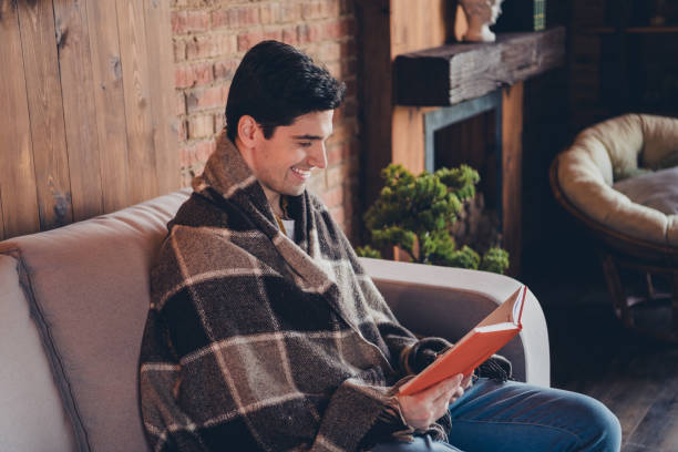 istock Young man enjoying a relaxing weekend at home reading a book in a cozy loft interior 2189753150
