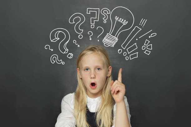 istock Excited child girl student with yellow light bulb and question marks on school blackboard background. Creativity, education and idea concept 2189753623