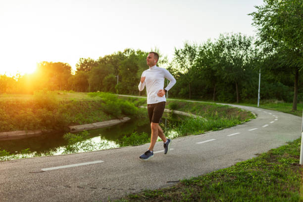 istock Young man running in park by the river at sunset 2189754500