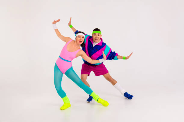 istock Two cheerful people in vibrant retro sportswear posing energetically in a bright studio, showcasing colorful 80s fashion and dynamic moves. 2189754758