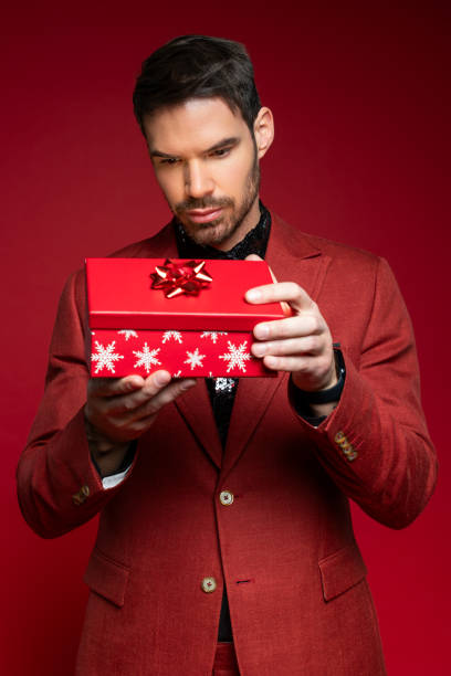 istock Man in Stylish Red Suit Holding Red Gift Box 2189755820