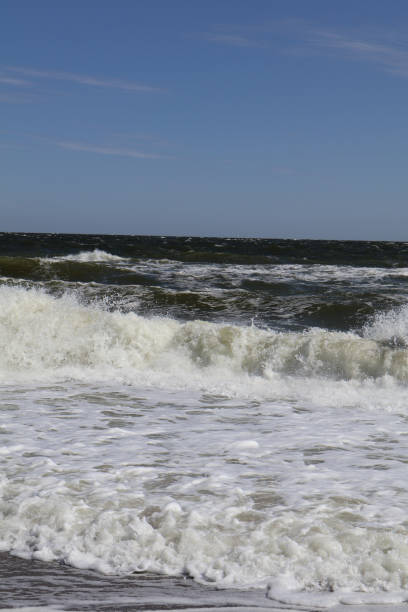 istock Ocean waves crashing on the sandy beach under a vibrant blue sky, creating a dynamic seascape with white foam and natural energy 2189755936