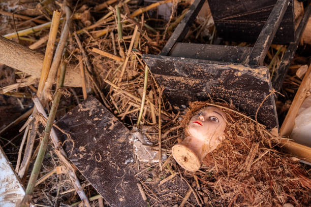 A doll head trapped in plastic garbage and fishing line on the sandy beach. Plastic pollution and environmental issues concept.
