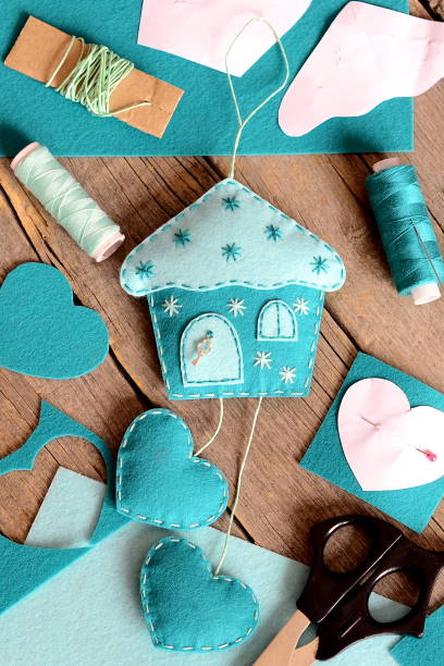 istock Felt house with hearts ornament, tools and materials for hand making felt crafts, paper patterns on wooden table 2189756926