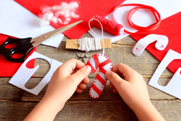 istock Child holds a Christmas felt candy cane in his hands. Materials and tools to create Christmas tree decorations 2189756927