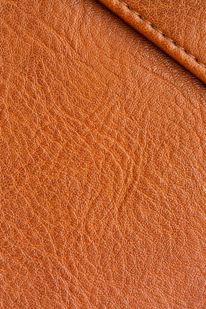 Close-up macro orange synthetic leather background,Natural, genuine orange leather texture close up, macro. Structure of glossy leatherette, artifical skin surface with embossing pattern. Background,