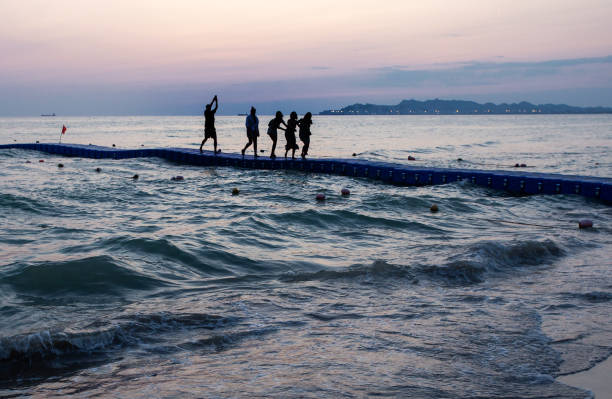 People move on a pontoon bridge in the sea towards the shore